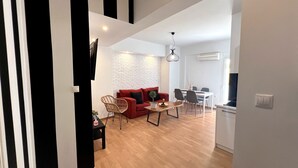 A modern living space with a red sofa, wooden dining table, and a white brick wall. - Allure Athens Urban Suites (Athens)