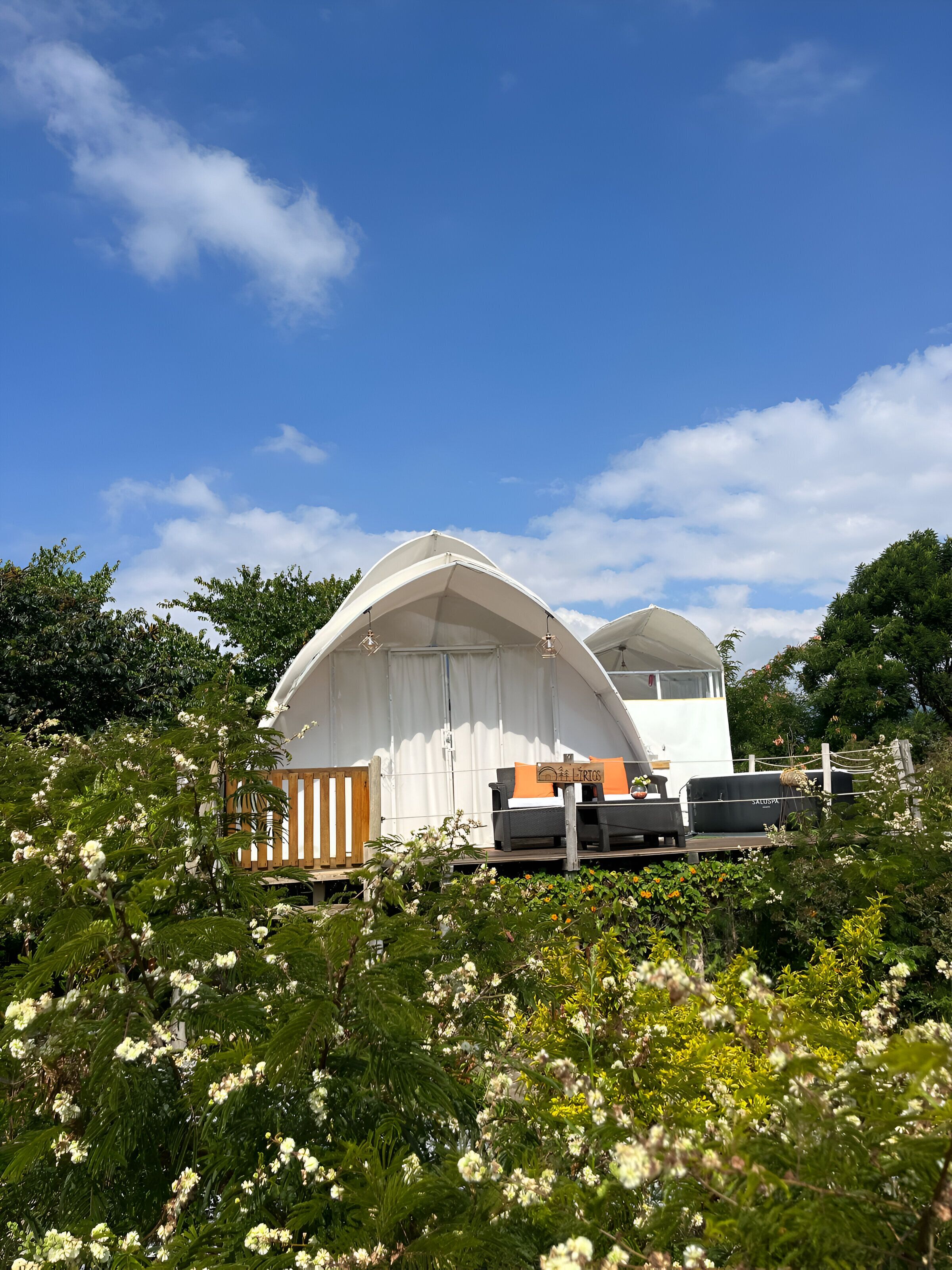 A white tent-like structure with a bench and grill in front.