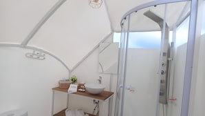 Un baño compacto de estilo tienda, en color blanco, con ducha, inodoro y lavamanos.