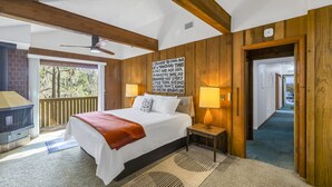 Ein Schlafzimmer mit einem Bett, Nachttischlampen, einem Kamin und Blick ins Freie.