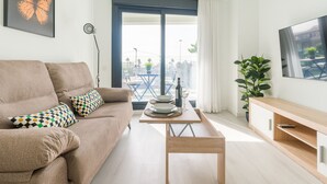 A modern living room with a sofa, a coffee table, a TV, and a balcony with a view.