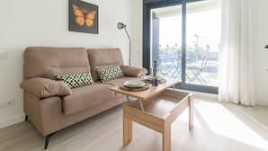 A modern living room with a sofa, a coffee table, and a large window with a view of the city.