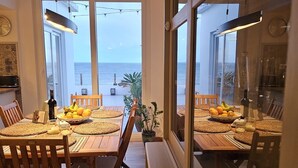 Un coin repas avec vue sur la mer, des meubles en bois et une plante en pot.