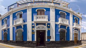 Um edifício azul e branco com entrada central, varandas e um terraço coberto.