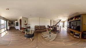 A spacious living area with a glass coffee table, leather sofa, and a television.