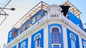A historic building with a blue facade, white trim, and ornate balconies.