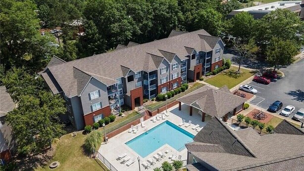A multi-story residential building with a swimming pool and a parking area. - 4 Bed 4 Bath Condo Near Campus! (Auburn)