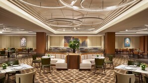 A spacious hotel lobby with a central seating area, multiple dining tables, and a large decorative plant. - The TianJin eye URcove hotel (Tianjin)