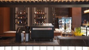 A modern bar area with a coffee machine, shelves of liquor bottles, and a refrigerated display. - The TianJin eye URcove hotel (Tianjin)