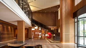 A spacious lobby with a central staircase, a reception area, and a large glass window offering a view of the outdoors. - The TianJin eye URcove hotel (Tianjin)