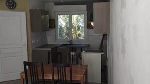 A compact kitchen with a dining area, a window, and a clock on the wall. - 1 Colocation Chambre Dans Maison Proche Paris, Orly (Antony)