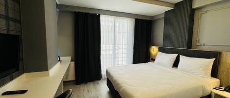 A hotel room with a bed, bedside table, lamp, and a TV on a stand.