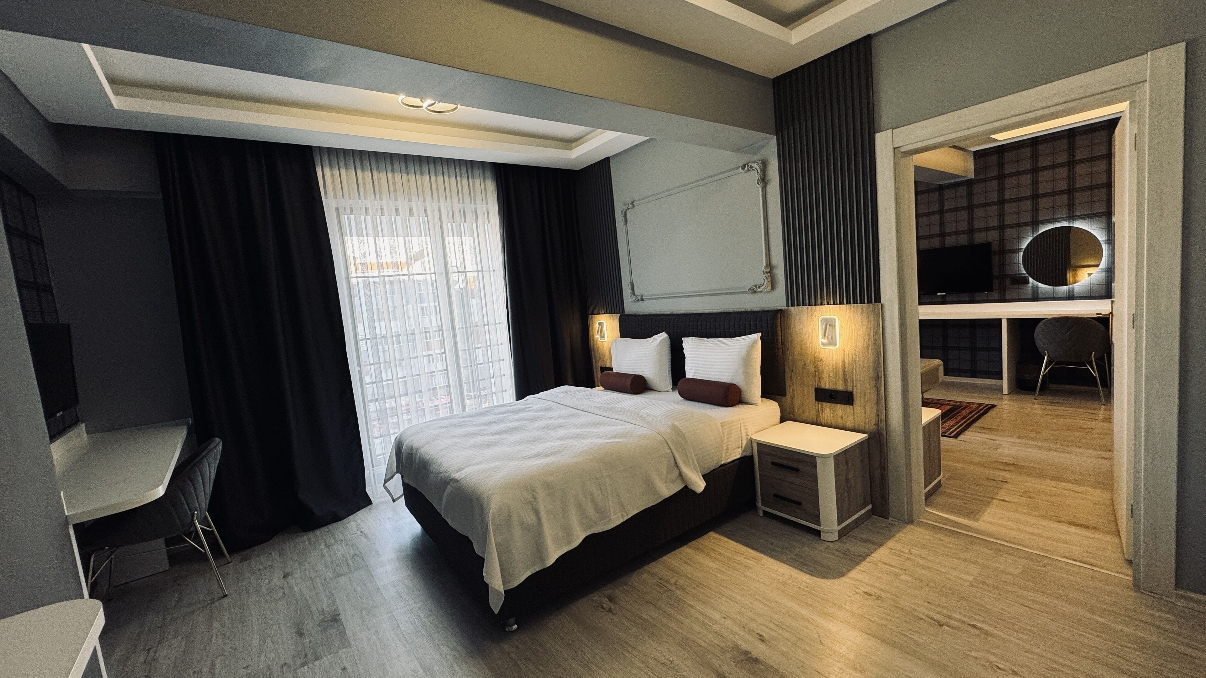 A modern hotel room with a large bed, bedside tables, a desk, and a TV.