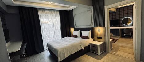 A modern hotel room with a large bed, bedside tables, a desk, and a TV.