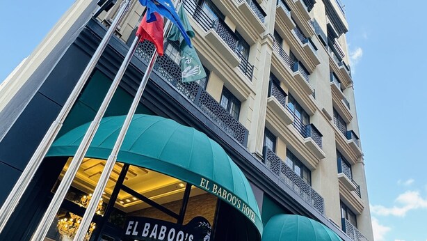 Un hotel de varios pisos con balcones y un cartel que dice 'El Babo's Hotel'.