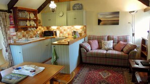 A cozy kitchen with a central island, a dining table, and a plaid sofa. - The Granary - Lanjeth (St Austell)