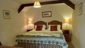 A bedroom with a bed, two bedside lamps, a wooden headboard, and a hanging light fixture.