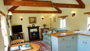 A cozy living room with a wooden dining table, a sofa, and a kitchen area with light blue cabinets.