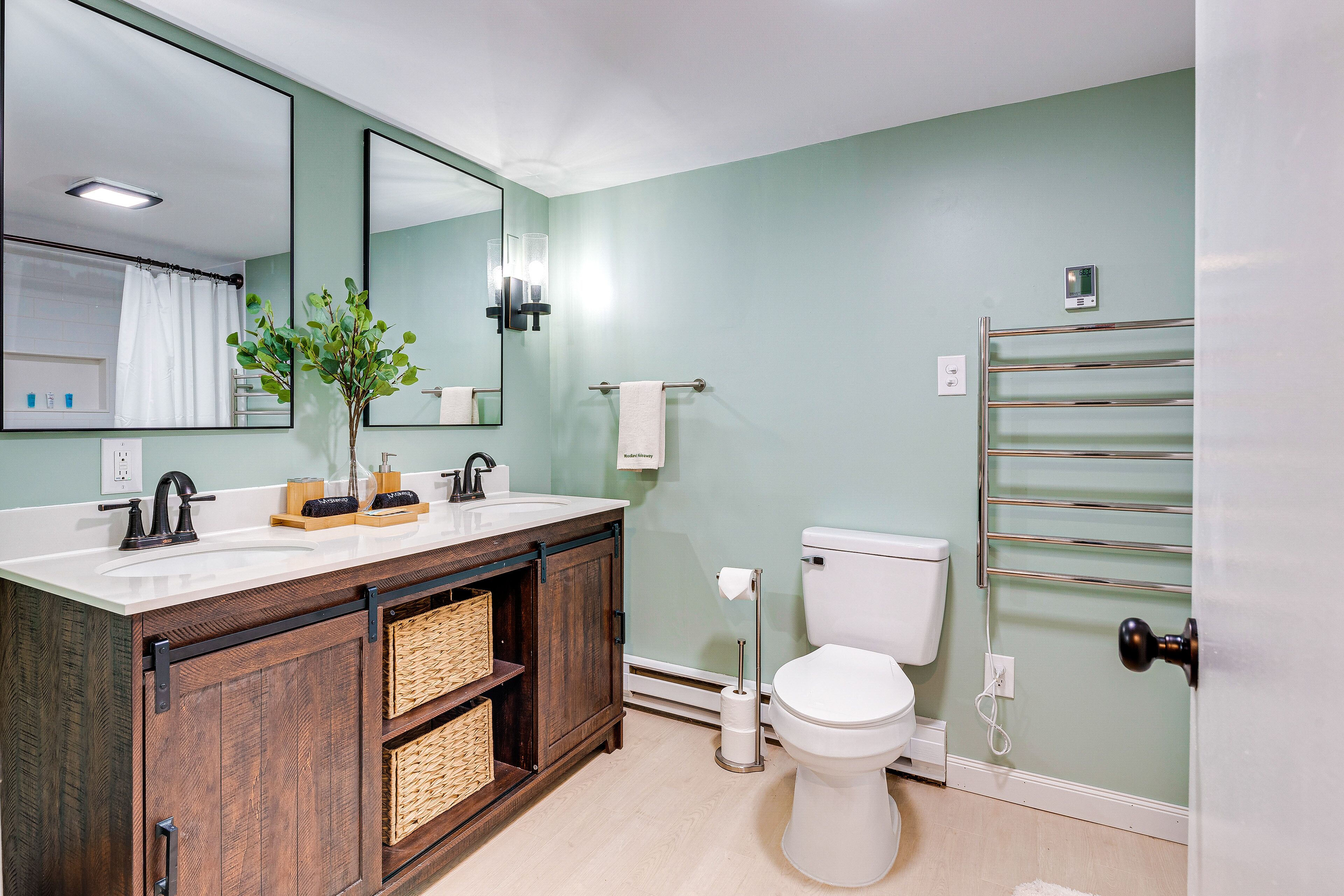 Een badkamer met een wit wastafel, donker houten wastafelmeubel, een wit toilet en een douchecabine van glas.