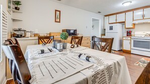 A dining area with a table set for four, a microwave, and a refrigerator in the background. - Charming Satsuma Home ~ 14 Mi to Mobile! (Satsuma)