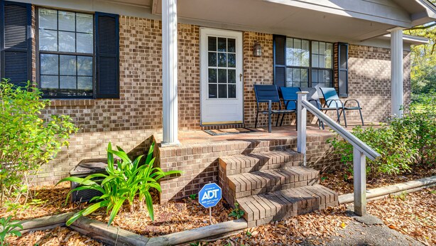 A brick house with a front porch, a door, and two chairs. - Charming Satsuma Home ~ 14 Mi to Mobile! (Satsuma)