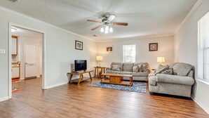 A living room with hardwood flooring, a ceiling fan, a television, a sofa, a coffee table, and a rug. - Charming Satsuma Home ~ 14 Mi to Mobile! (Satsuma)
