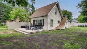 A single-story house with a sloped roof, a front porch with a bench, and a small deck area.