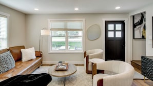 A modern living room with a leather sofa, a round coffee table, and a black door.