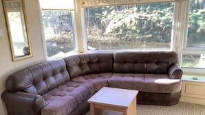 A large L-shaped sectional sofa with a wooden coffee table in a room with large windows. - Park Lodge sleeps 6 On Beautiful Rural Welsh Farm (Builth Wells)