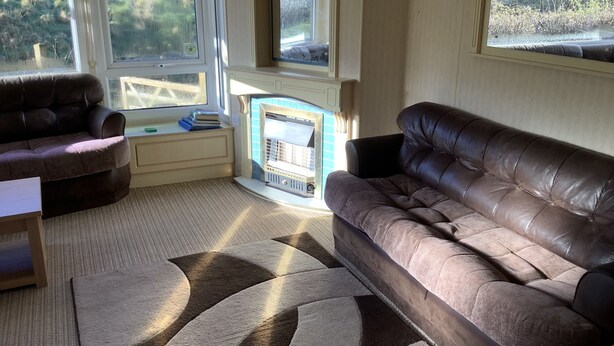A cozy living room with two leather sofas, a small table, and a fireplace. - Park Lodge sleeps 6 On Beautiful Rural Welsh Farm (Builth Wells)