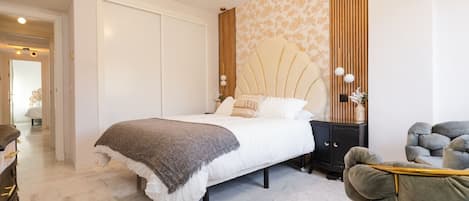 Un dormitorio con cama, mesita de noche y una silla.