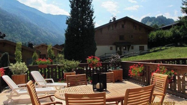 A patio with wooden chairs and tables, surrounded by potted plants and flowers. - Appartement Camille Bonaventure (Les Contamines-Montjoie)