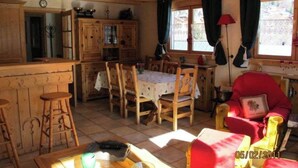 A cozy wooden cabin interior with a dining area, kitchen, and seating space. - Appartement Camille Bonaventure (Les Contamines-Montjoie)