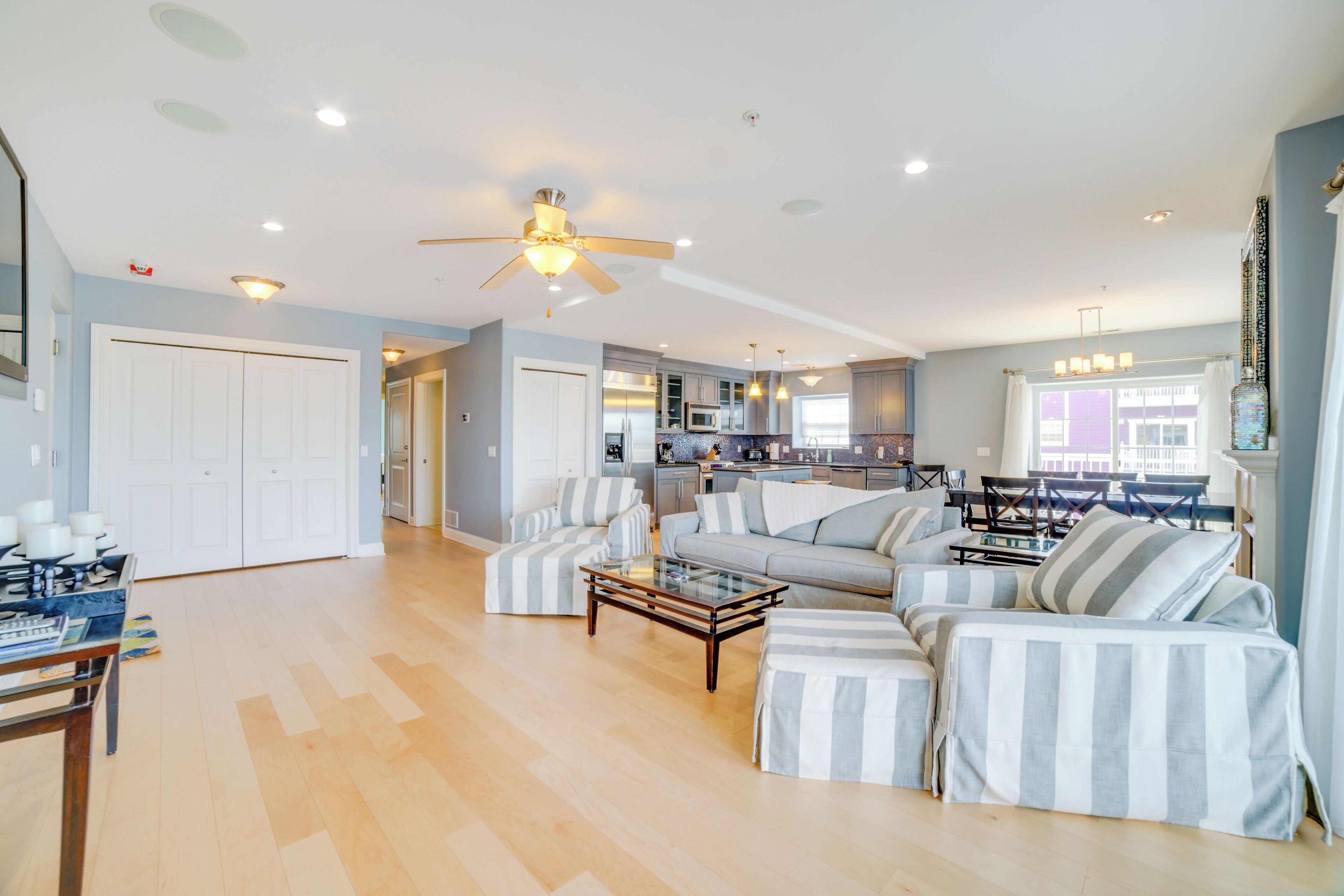 A spacious living room with a sofa set, a coffee table, and a dining area with a chandelier.