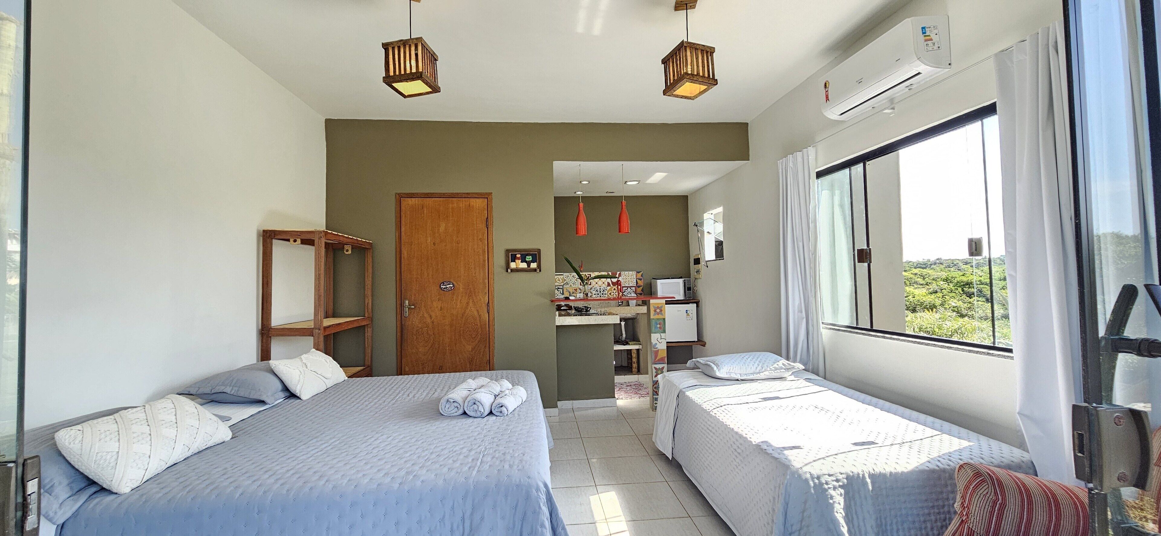 A bedroom with two beds, a desk, and a window with a view.