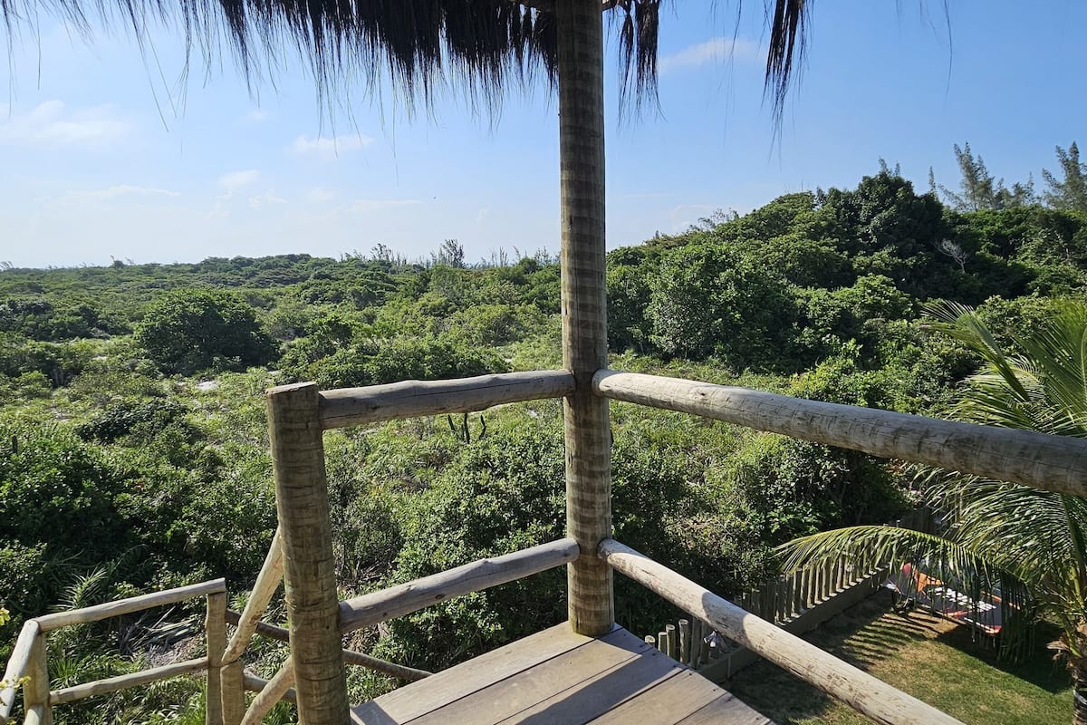 A wooden deck with a railing overlooking a lush green landscape.