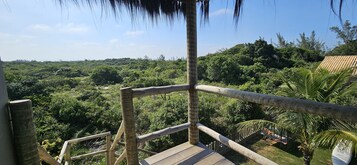 A wooden deck with a railing overlooking a lush green landscape.