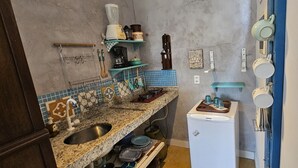 A kitchen with granite countertops, a sink, a refrigerator, and various kitchen utensils and appliances. - Kite Nomade (Arraial do Cabo)