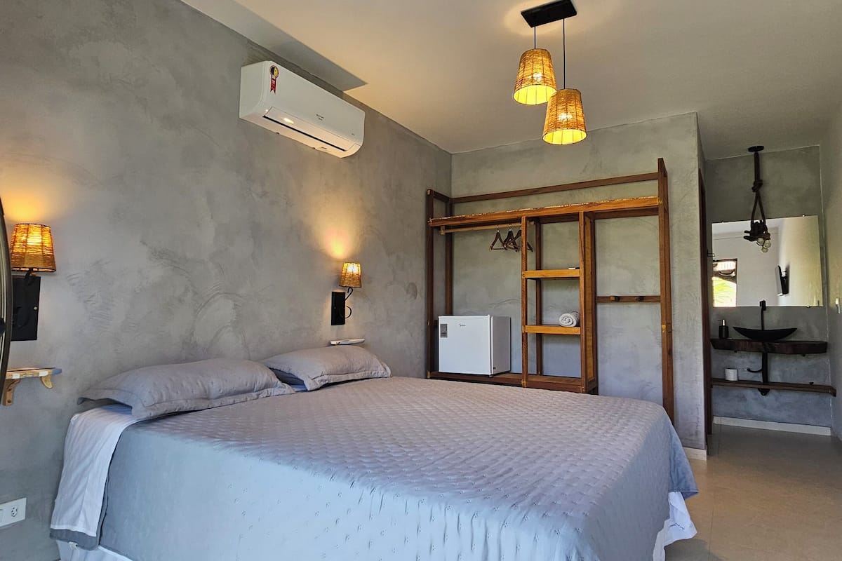 A bedroom with a bed, bedside lamps, an air conditioner, and a TV.