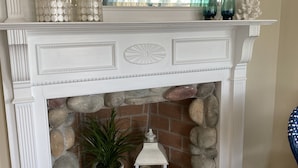 A fireplace with a stone surround, decorative mirrors, and potted plants. - BELLE of the BEACH: 30 ft to gorgeous PRIVATE BEACHFRONT home SLEEPS up to 13 (Wareham)