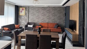 A modern living room with a dining area, featuring a sofa set, a coffee table, and a TV unit. - Villa mit Privatem Pool in der Nähe von Strand und Einkaufszentrum (Kuşadası)
