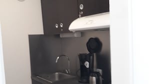 Uma cozinha compacta com pia, cafeteira e máquina de lavar louça.