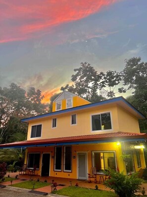 A two-story building with a flat roof, multiple windows, and a covered porch area.