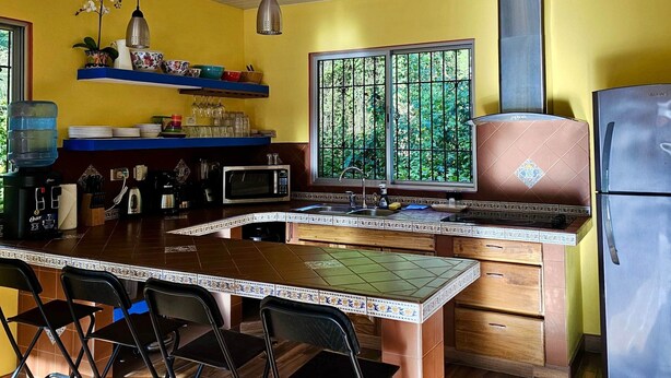 A kitchen with a central island, a microwave, a sink, and a refrigerator. - The Spot @ Cocles #1 (Cocles)