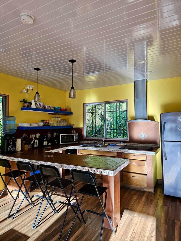 Una cocina con una isla central, microondas, fregadero y refrigerador.