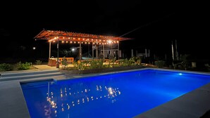 Une piscine dotée d’un espace couvert et illuminée de guirlandes lumineuses.