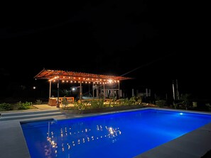 A swimming pool with a covered area and string lights.