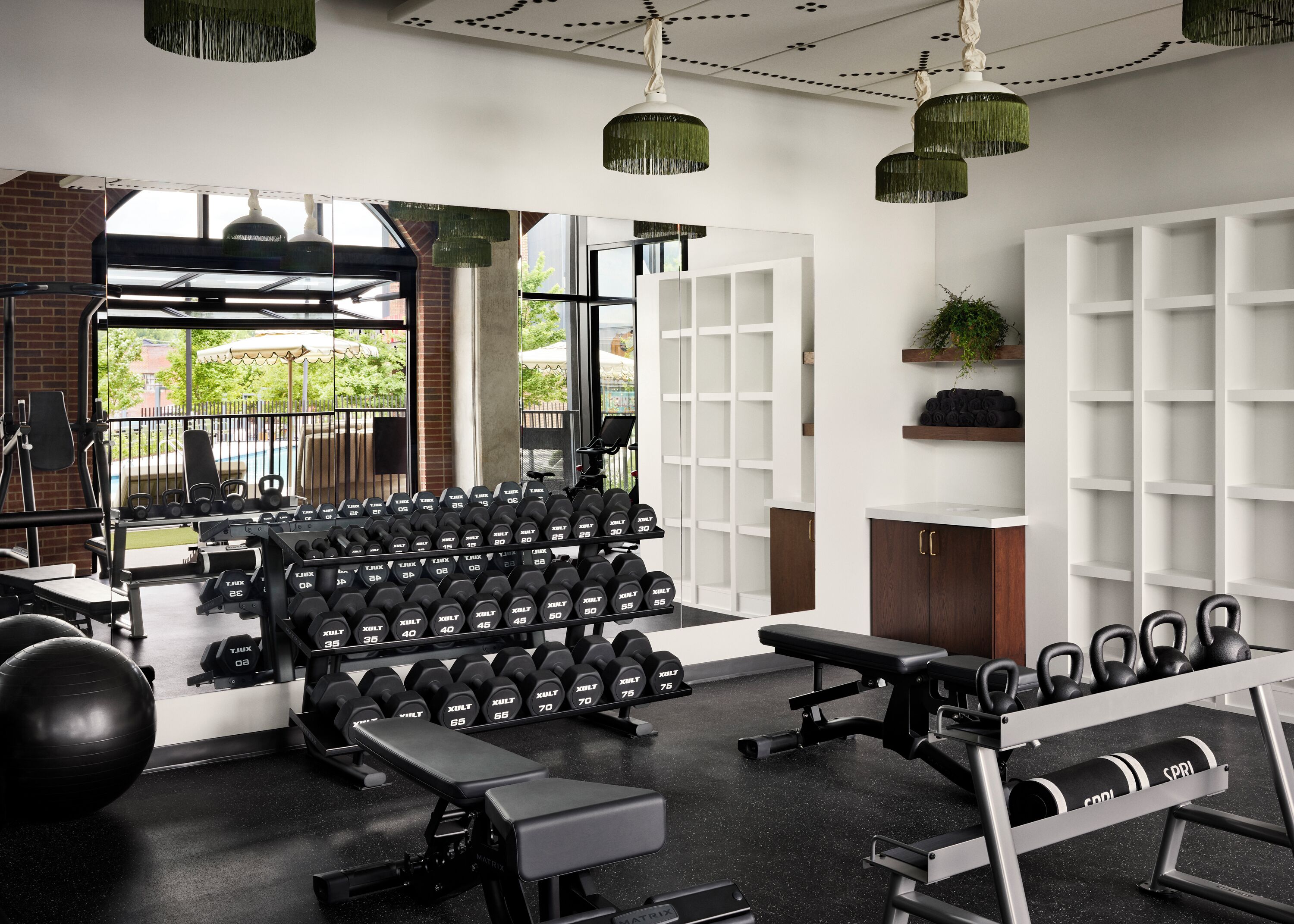 A gym with various exercise equipment, including dumbbells, kettlebells, and a bench.