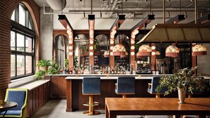 A bar area with a wooden counter, bar stools, and hanging pendant lights.