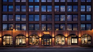 A multi-story brick building with large windows and arched entrances.